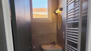 Une petite salle de bain avec une fenêtre, un lavabo et un porte-serviettes.