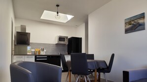 Une cuisine moderne avec un coin repas, comprenant une table à manger avec des chaises, un canapé et un luminaire suspendu au plafond.