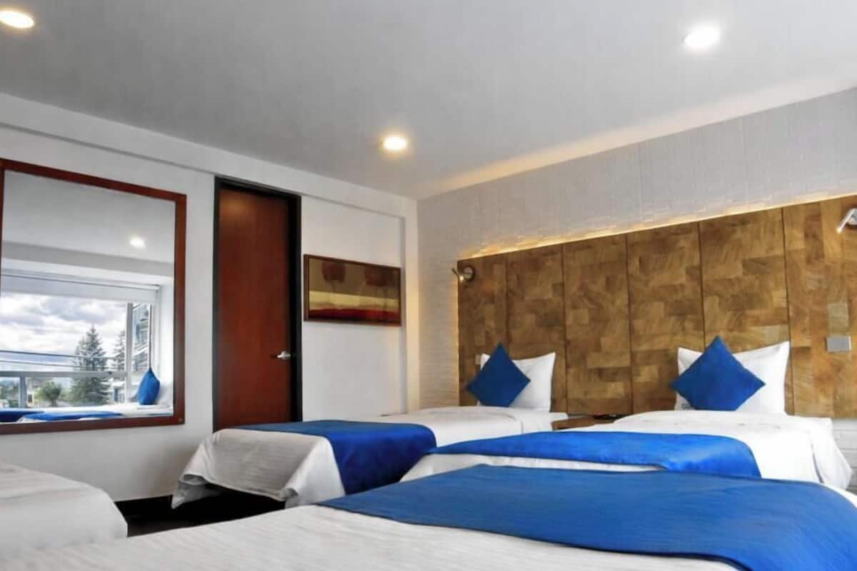 A hotel room with two beds, a wooden headboard, a window with a view, and a door.