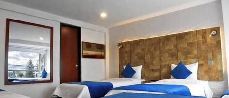 Habitación de hotel con dos camas, cabecero de madera, ventana con vistas y una puerta.