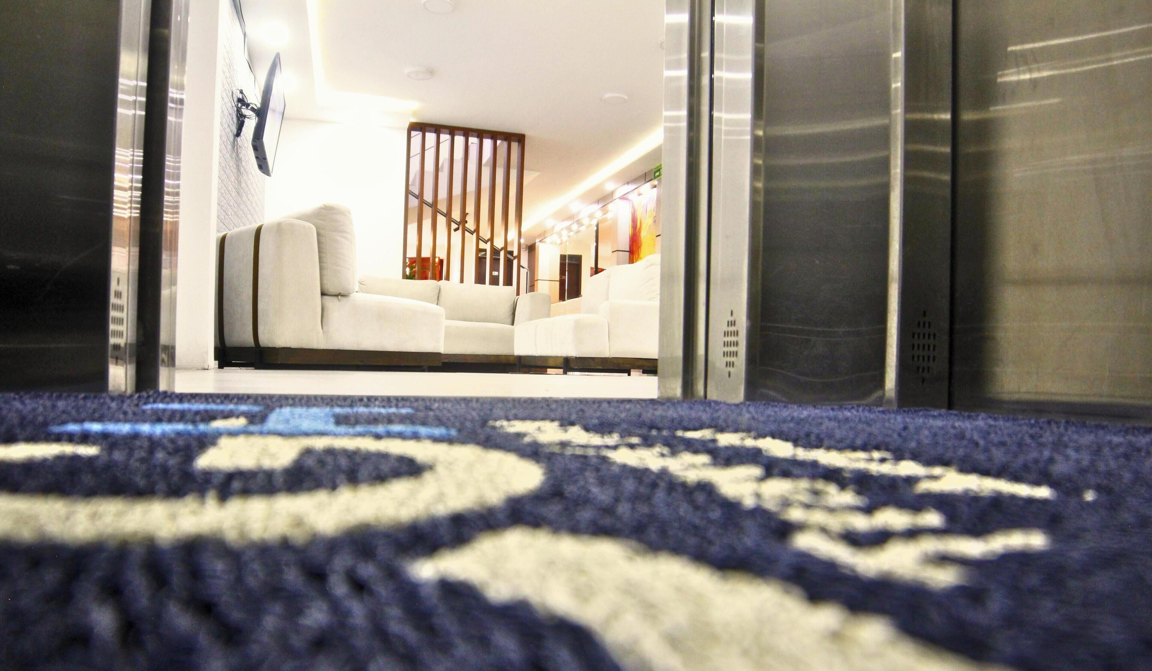 An interior view of a hotel lobby with a patterned carpet, a sofa, and a wooden partition.
