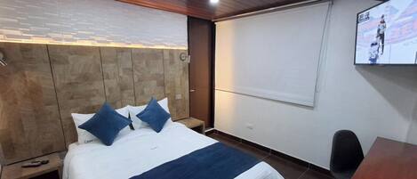 A hotel room with a bed, a TV, a desk, and a chair.