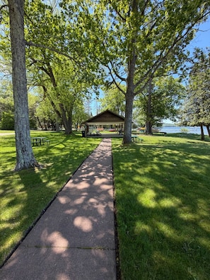 Ein Park mit einem gepflasterten Weg, Picknicktischen und einem überdachten Pavillon.