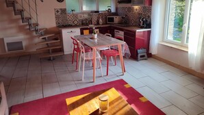 Una cocina compacta con comedor, una escalera y un ventanal.