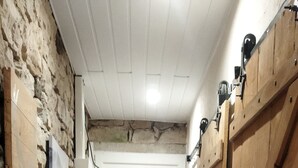 Un pasillo estrecho con paredes de piedra, puertas de madera y suelo de madera rústica.