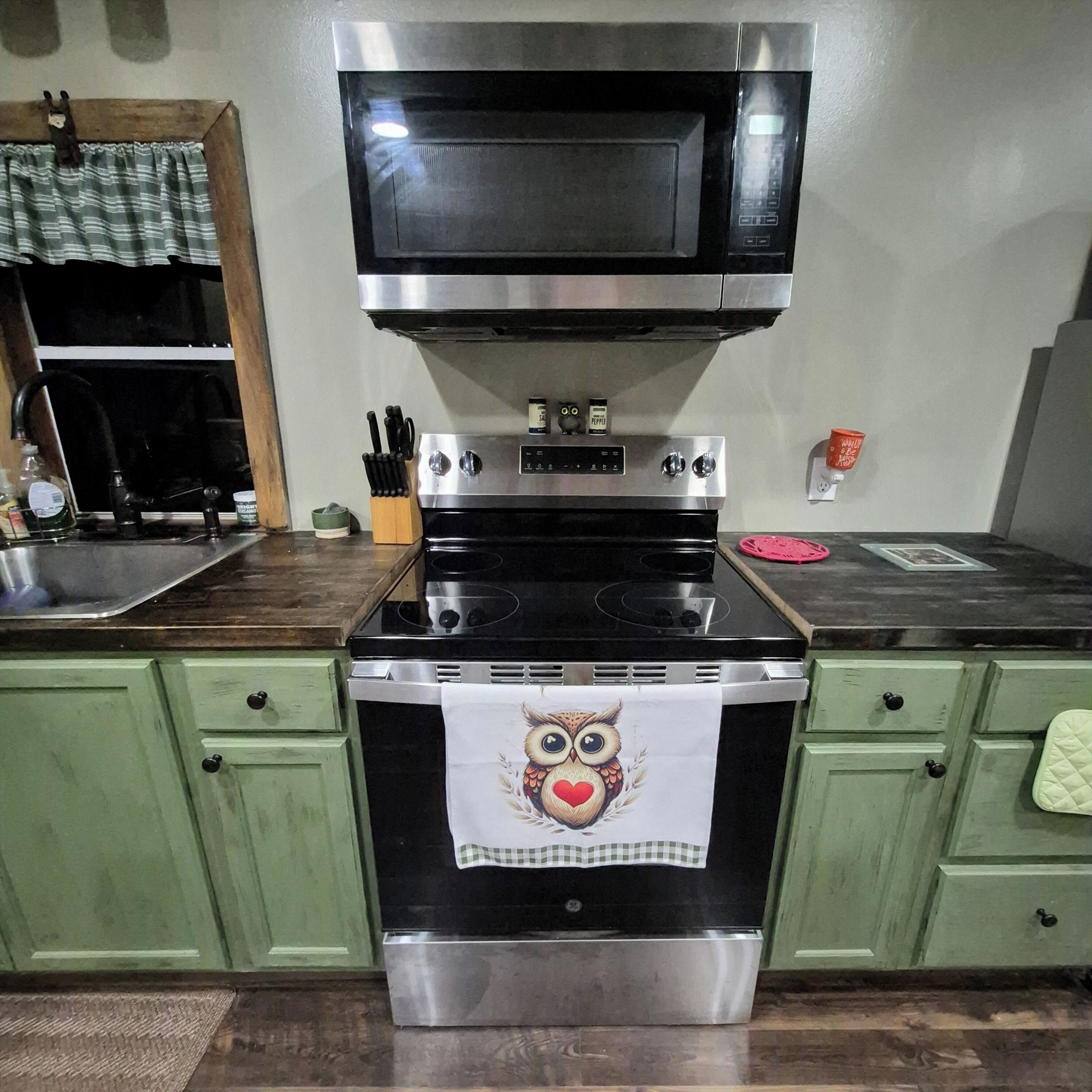 A kitchen with a stainless steel stove, a microwave above it, and green cabinets.
