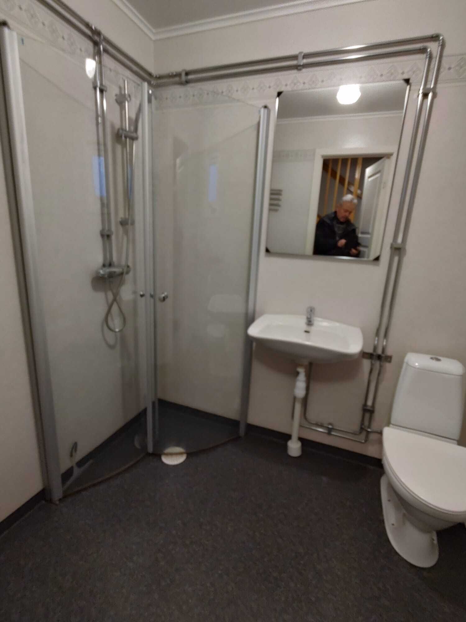 Une petite salle de bain fermée, équipée d’une douche, d’un lavabo et de toilettes.