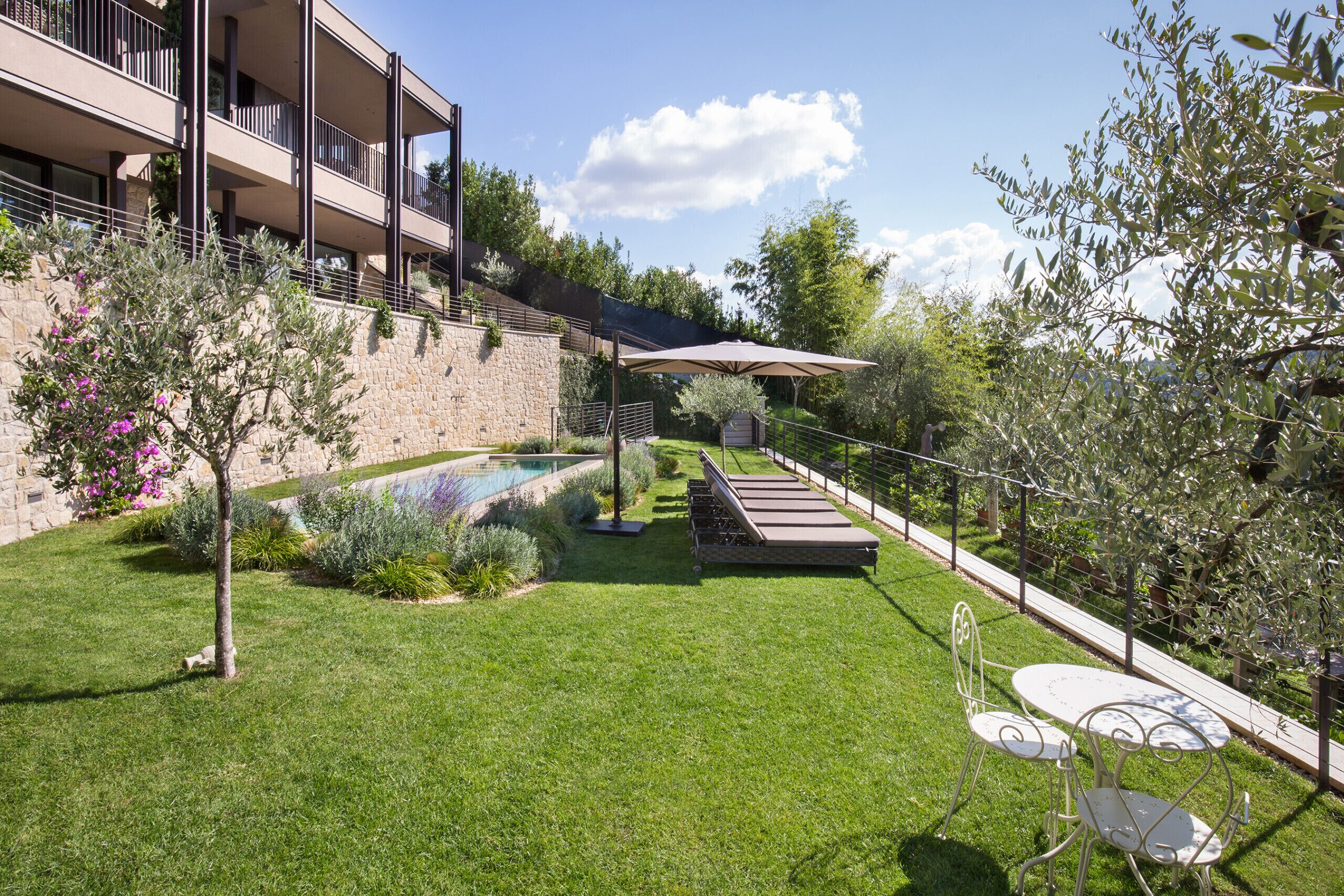 A well-maintained backyard with a swimming pool, outdoor seating, and a stone wall.