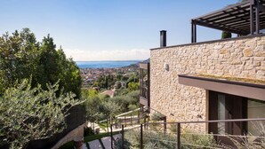 A stone building with a balcony overlooking a scenic view of a town and the sea. - Apartment Sole in Residence Villa Miralago (Costermano)