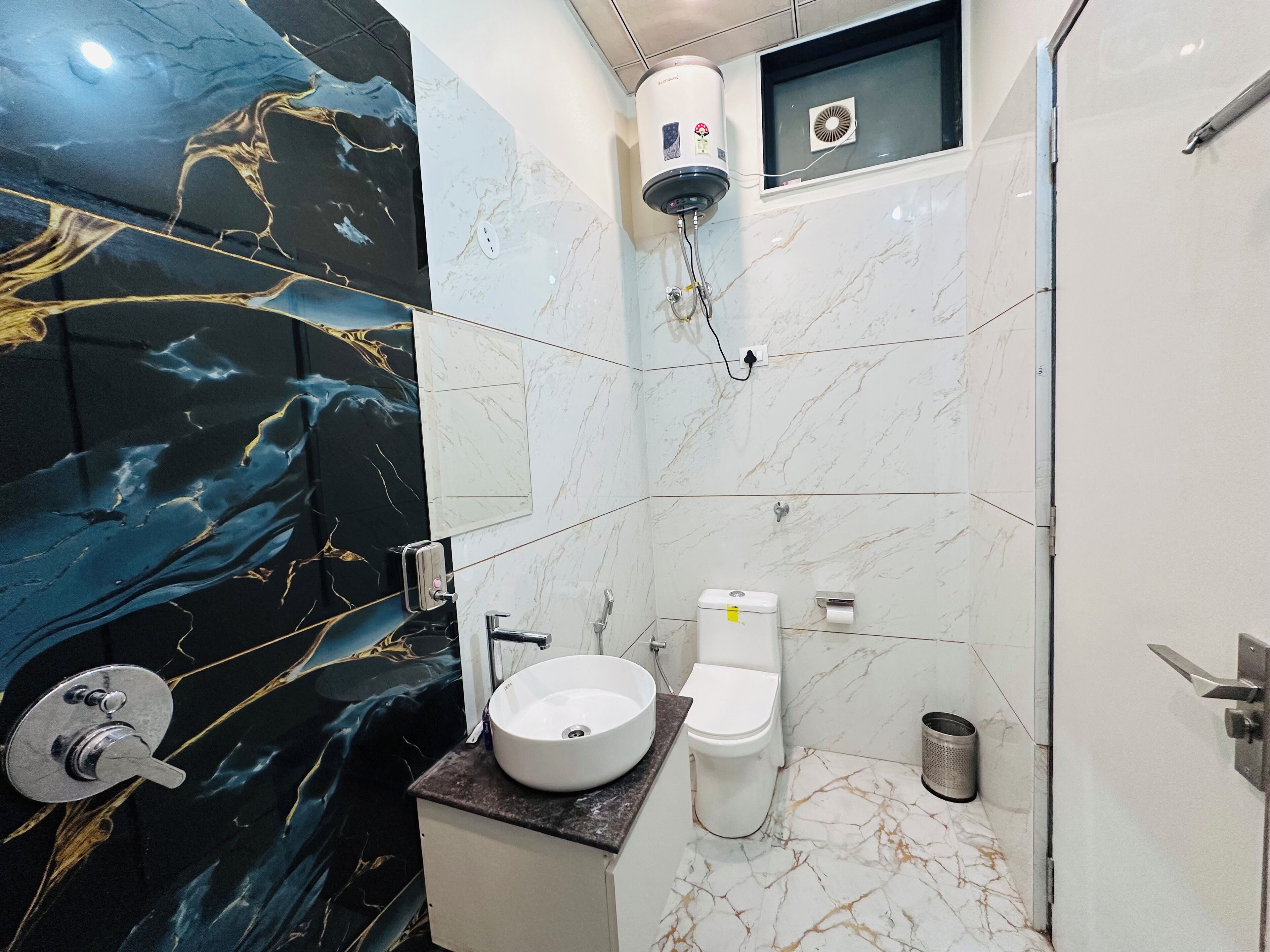 Un baño con pared de mármol, un lavabo, un inodoro y una ducha.