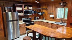 Uma cozinha moderna com armários de madeira, eletrodomésticos de aço inoxidável e uma ilha grande com banquetas.