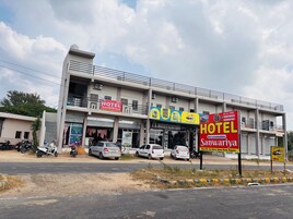 Un edificio de varios pisos con un letrero llamativo para un hotel llamado 'Sanwariya' y una tienda de personalización de automóviles.