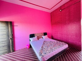 Una habitación con una cama, una puerta de madera y una pared rosa.