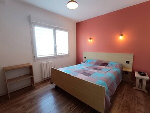 Une chambre à coucher avec un lit, une fenêtre, une table de chevet et une commode.