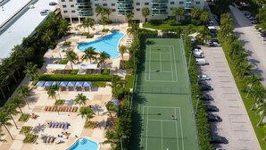 Eine Luftaufnahme eines Resorts mit Schwimmbad, Tennisplätzen und einem Parkplatz.