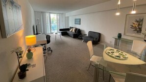 Ein modernes Hotelzimmer mit einer Couch, einem Esstisch mit Stühlen, einer Lampe und einem Glastisch.