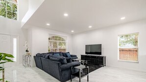 Ein modernes Wohnzimmer mit einem Ecksofa, einem Flachbildfernseher und einem minimalistischen Design.