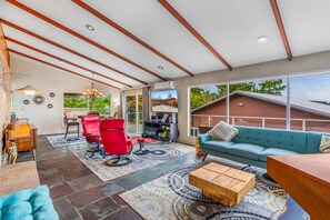 A spacious living area with a large window, a sofa, a coffee table, and a TV.