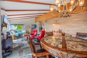A spacious living area with a fireplace, a round wooden table, and comfortable seating.