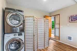 A laundry area with two Samsung washing machines, a wooden partition, and a door leading to a balcony.
