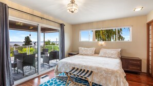 Una camera da letto con un letto grande, vista sull'esterno e un balcone con sedie.