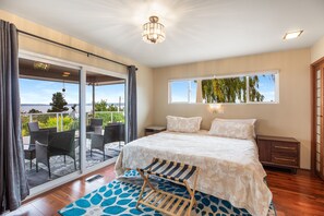 Ein Schlafzimmer mit einem großen Bett, Blick ins Freie und einem Balkon mit Stühlen.