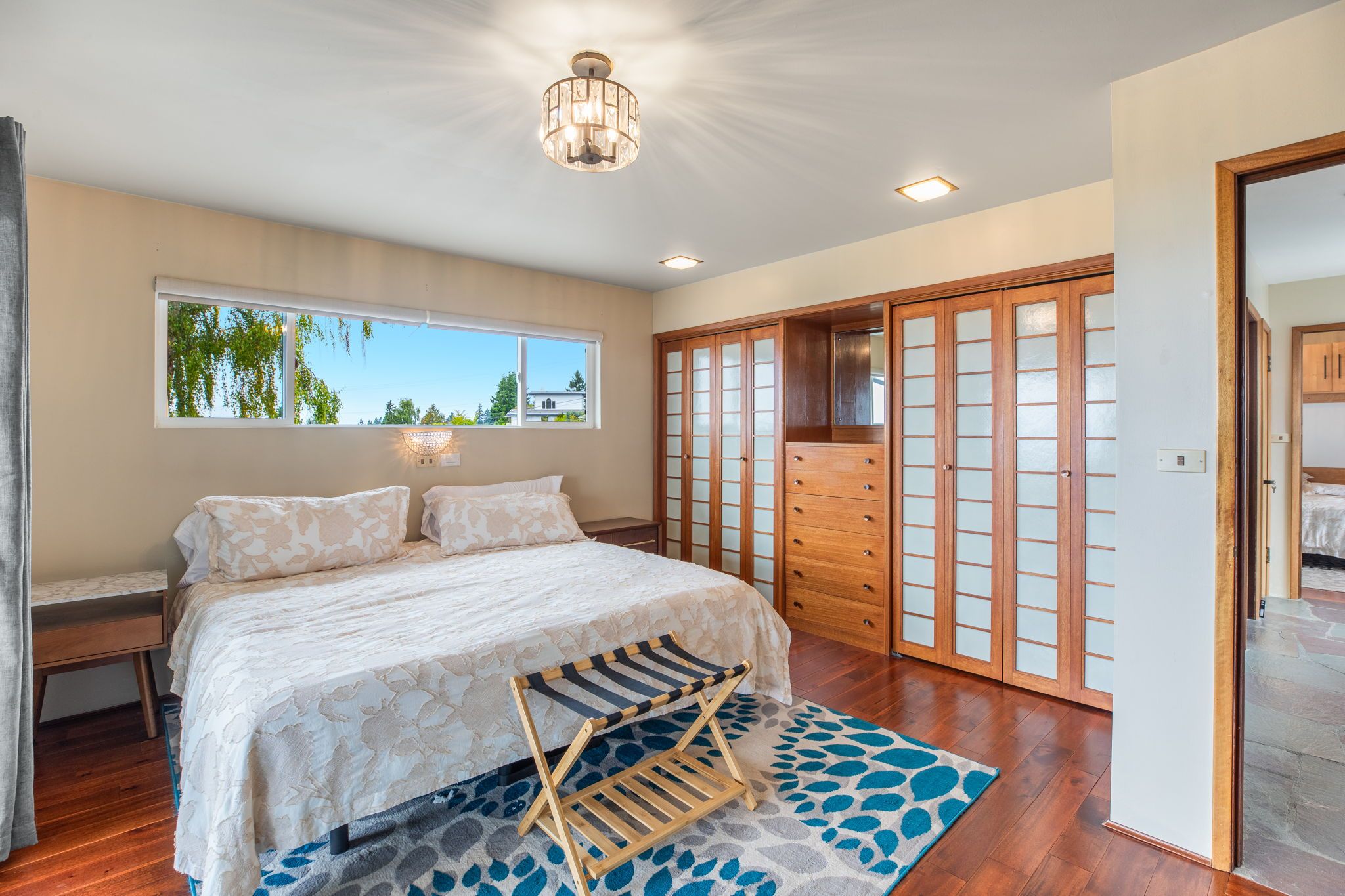 A bedroom with a bed, a window, a wardrobe, and a ceiling light.