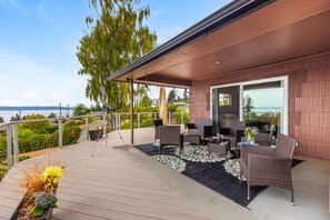 A covered outdoor area with wicker furniture, a telescope, and a view of the water.