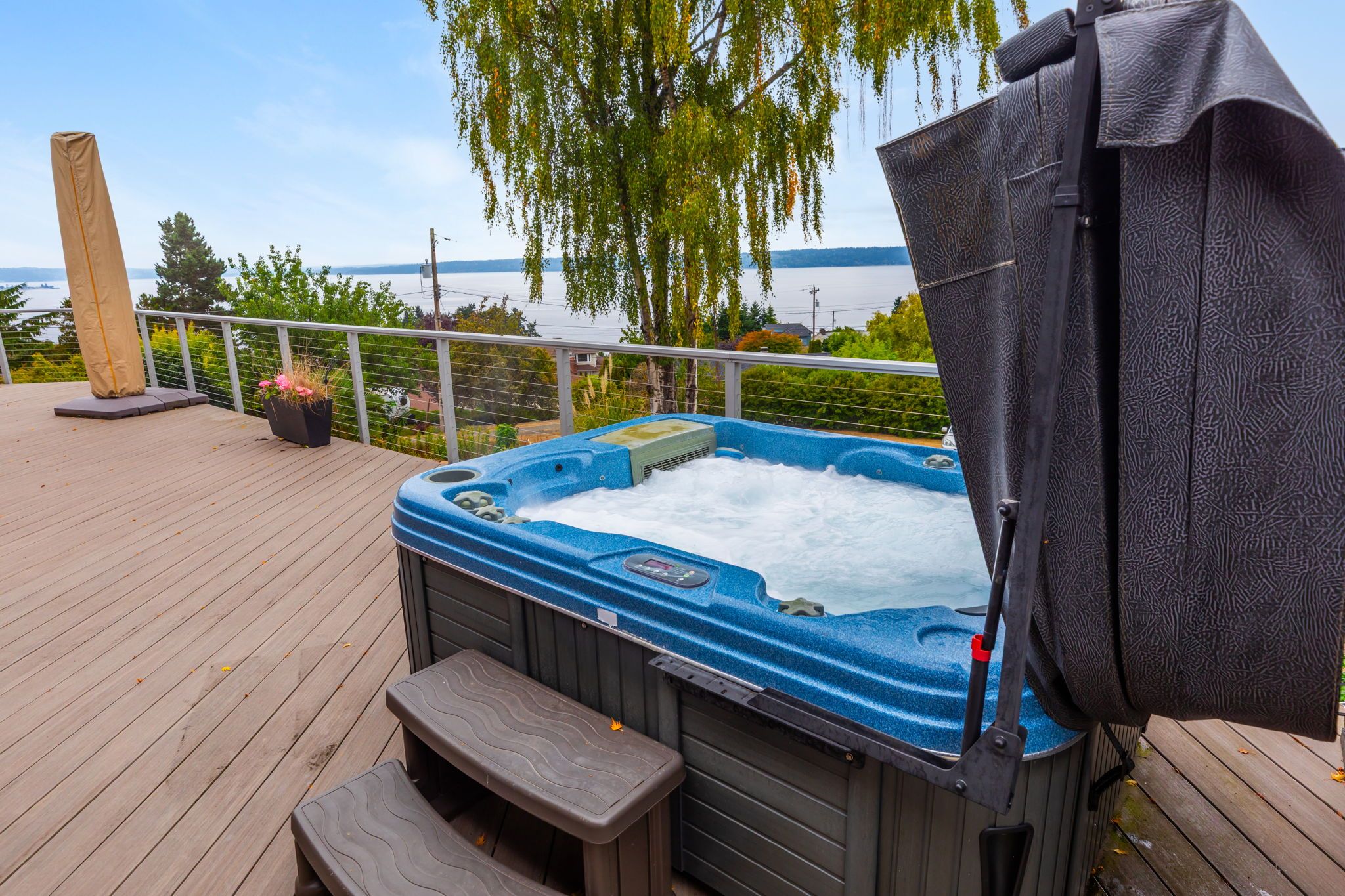 Ein Whirlpool auf einer Holzterrasse mit Blick auf einen See und Bäume.