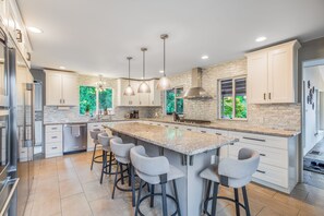 A modern kitchen with a large island, bar stools, and pendant lighting.