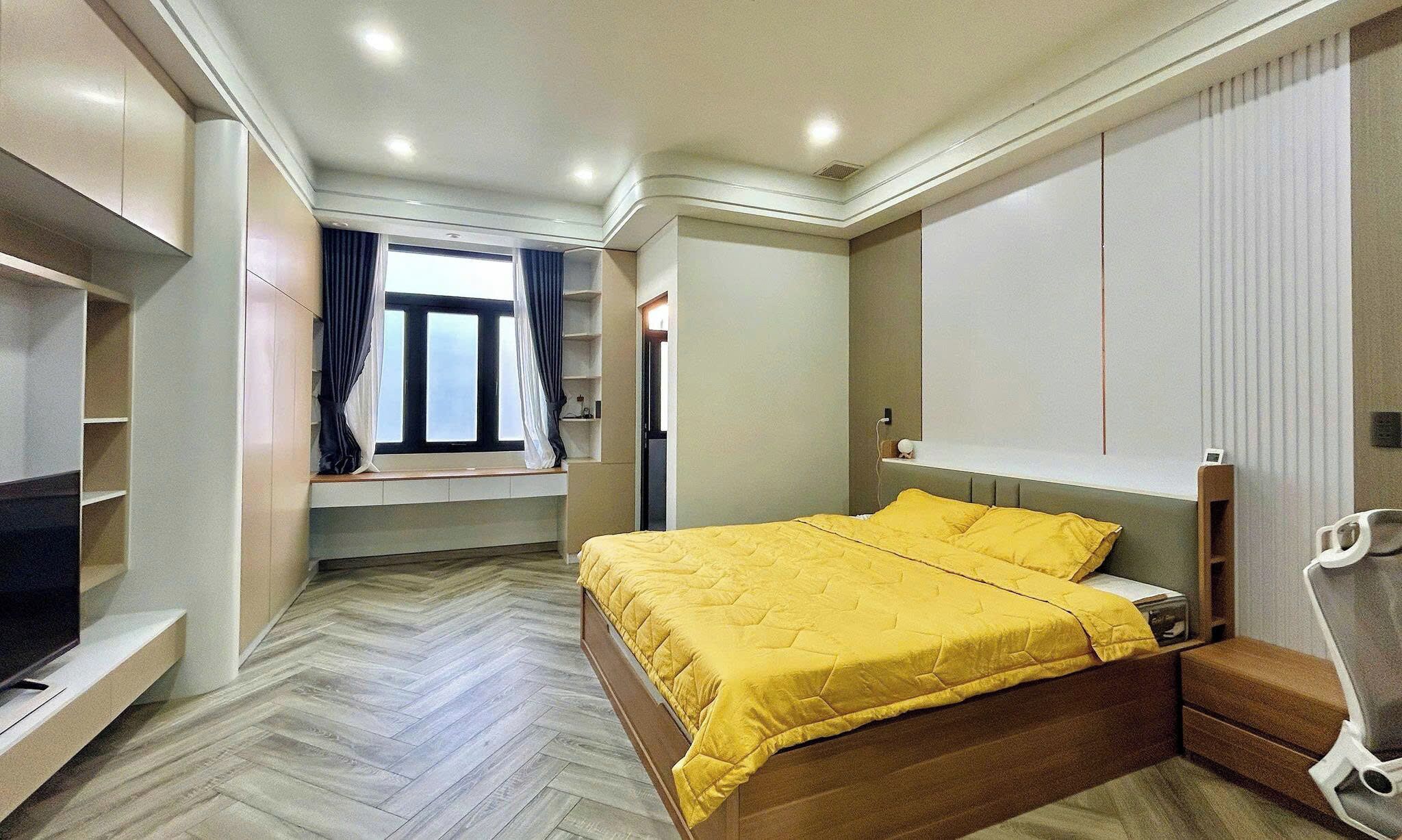 Un dormitorio con cama, televisor, armario y ventana con cortinas.