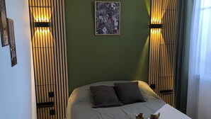 A neatly arranged bedroom with a bed, a bedside table with a tray of breakfast items, and a framed picture on the wall.
