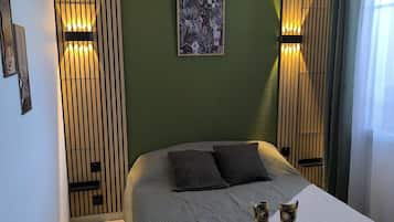Een netjes ingerichte slaapkamer met een bed, een nachtkastje met een ontbijtplateau en een ingelijste foto aan de muur.