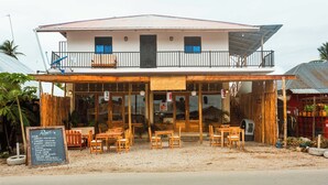 A two-story building with a balcony, wooden furniture, and a signboard. - Roots inn  (Paje)