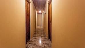 A narrow hallway with wooden doors on either side and a marble floor. - Roots inn  (Paje)