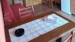 A compact kitchen with wooden cabinets, a dining table with a lace tablecloth, and a ceiling fan.
