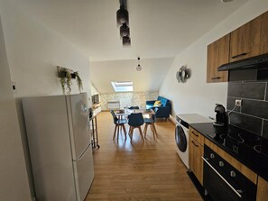 Una cucina moderna con frigorifero, lavatrice e zona pranzo con un divano blu e sedie di legno.