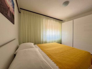 Une chambre à coucher avec un lit, des rideaux blancs et un tableau accroché au mur.