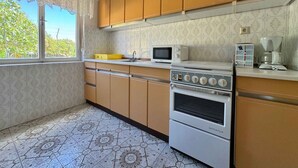 A kitchen with patterned tiles, wooden cabinets, a microwave, an oven, and a coffee maker. - Holiday apartment mit Klimaanlage und Terrasse (Krk)