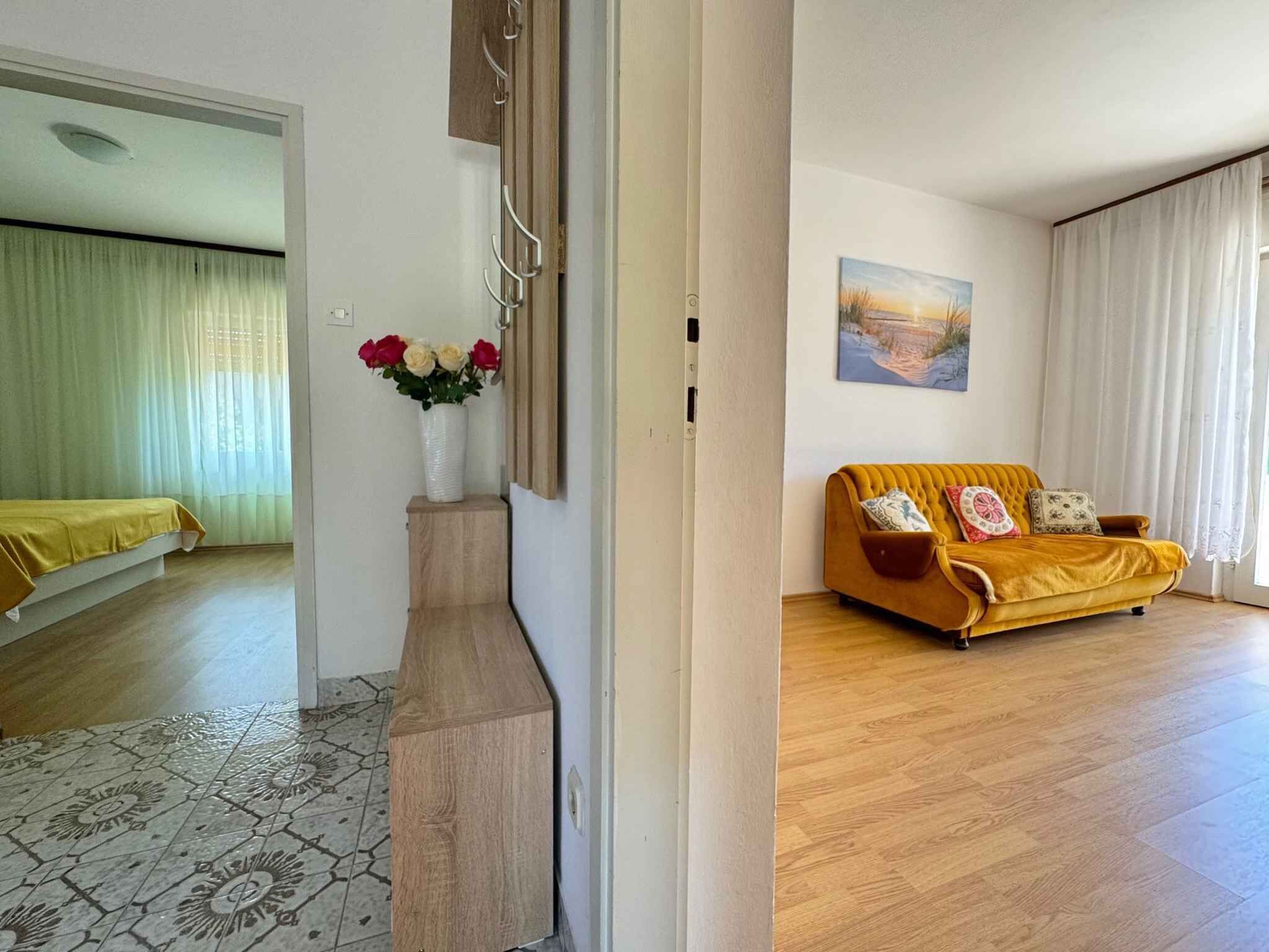 A room with a sofa, a painting, and a vase with flowers.