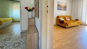 A room with a sofa, a painting, and a vase with flowers. - Holiday apartment mit Klimaanlage und Terrasse (Krk)