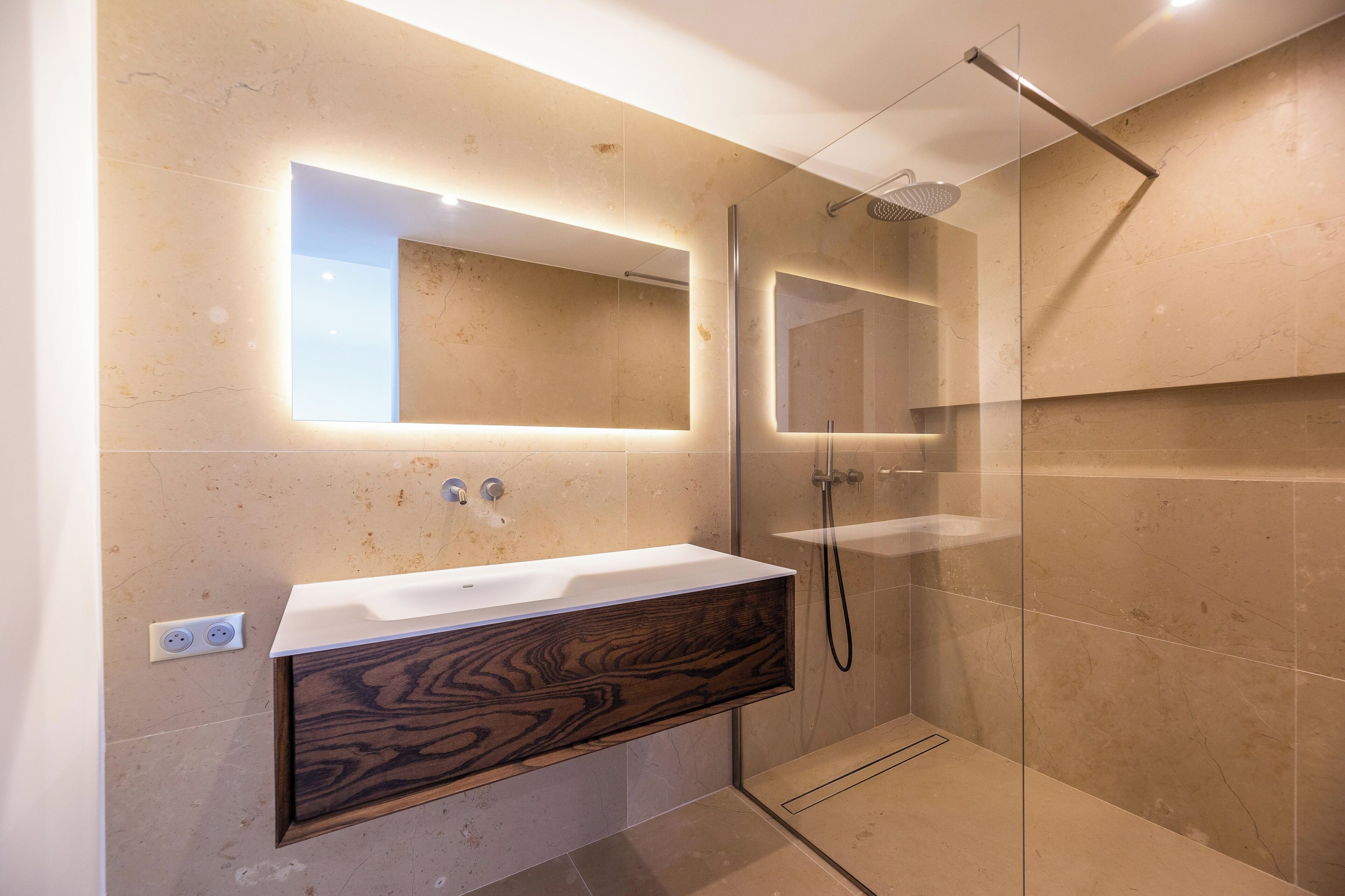 A modern bathroom with a wooden vanity, a large mirror, and a glass-enclosed shower.