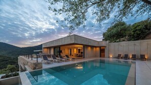 Un espace moderne aménagé au bord de la piscine, avec des chaises longues et une vue sur le paysage environnant.