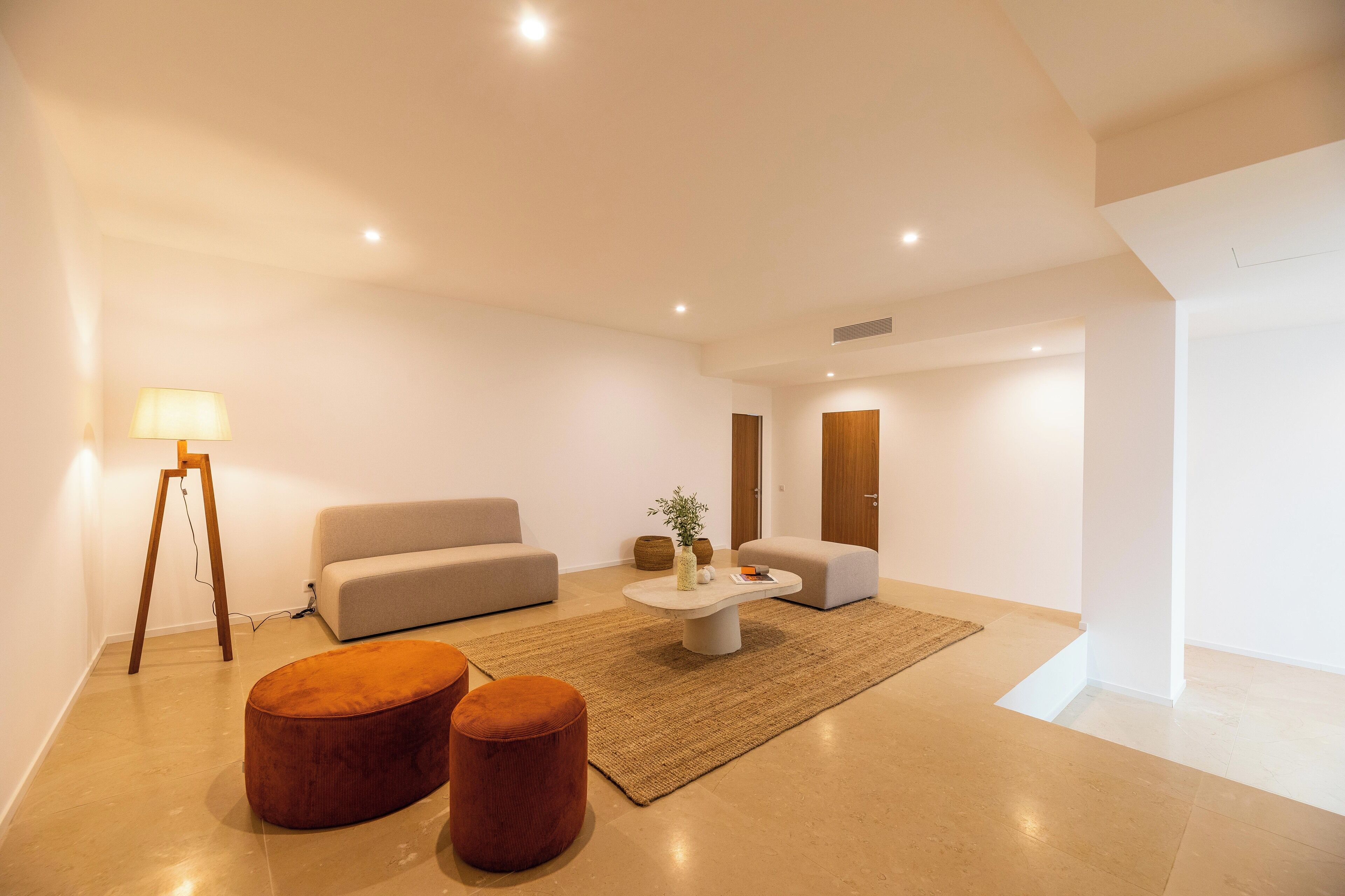 A modern living room with a sofa, ottomans, a coffee table, and a lamp.