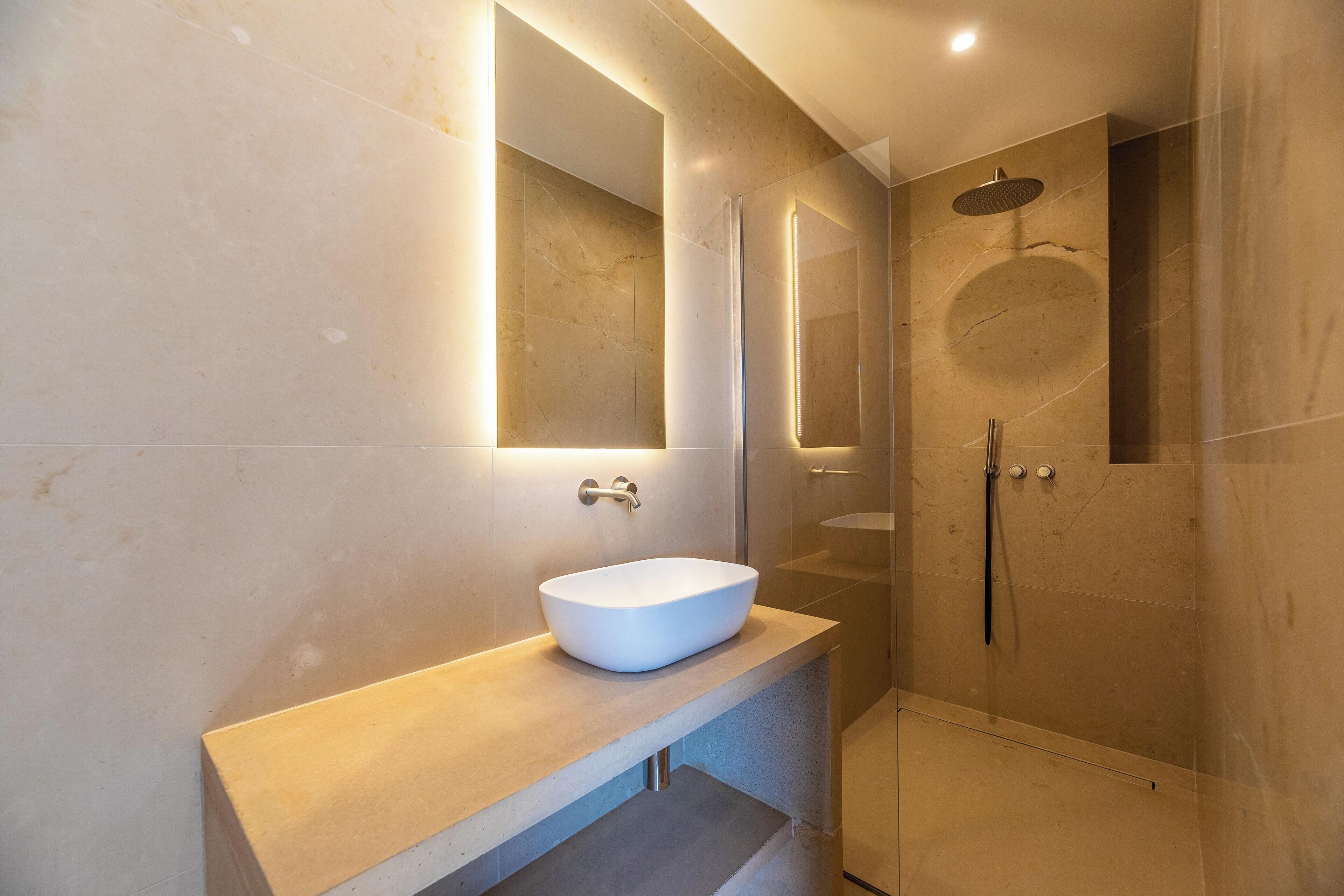 A modern bathroom with a large mirror, a vessel sink, and a walk-in shower.