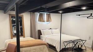 A modern bedroom with two beds, a hanging light fixture, and a wooden chair.