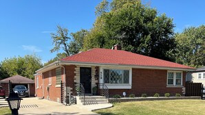 A single-story brick house with a red roof, a front porch, and a garage.