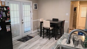 Una cocina compacta con comedor, un refrigerador con imanes, un lavamanos y una puerta con ventana.