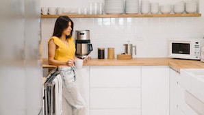 Une cuisine avec des armoires blanches, un plan de travail en bois et divers appareils de cuisine, notamment une machine à café et un four à micro-ondes.
