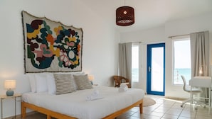 Une chambre avec un grand lit, une vue sur la mer et une porte bleue.